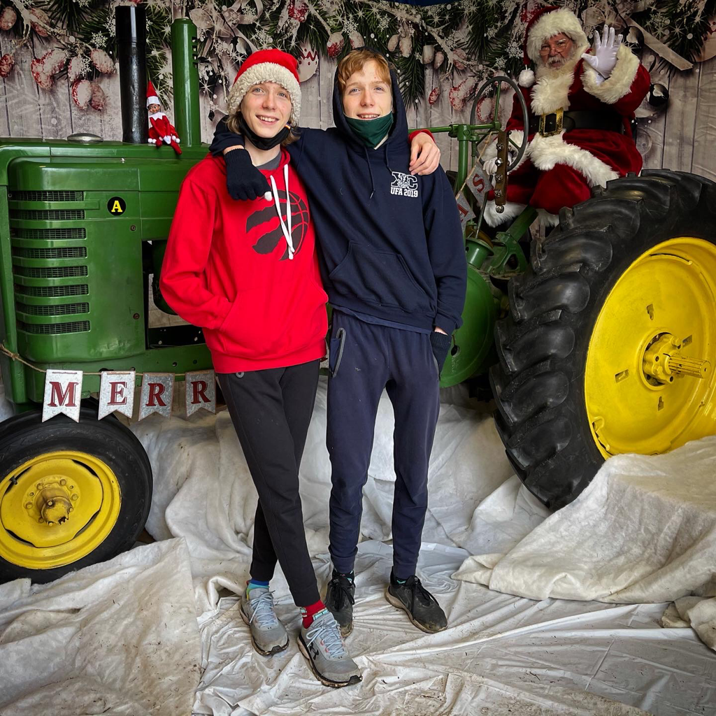Picture of teenage twins standing in front of a tracker with Santa riding on it