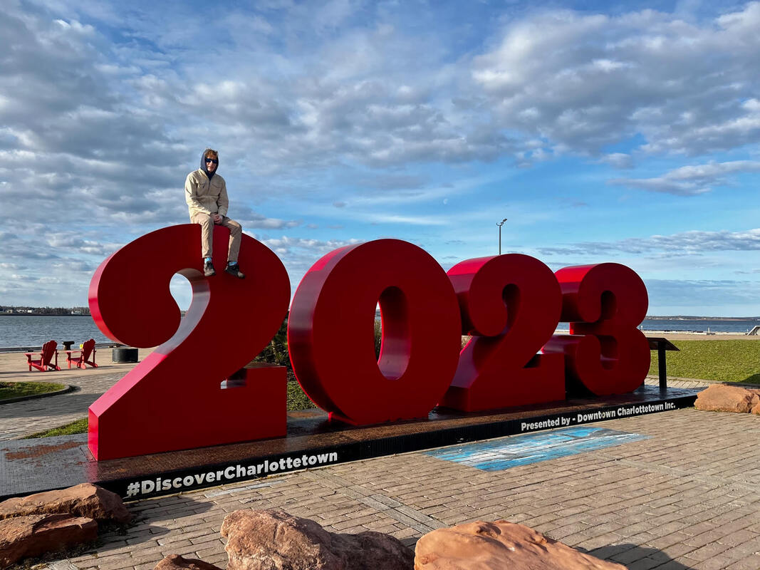 Simon Ormerod sitting on red 2023 sign in Charlottetown Picture